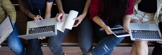 children holding laptops on bench